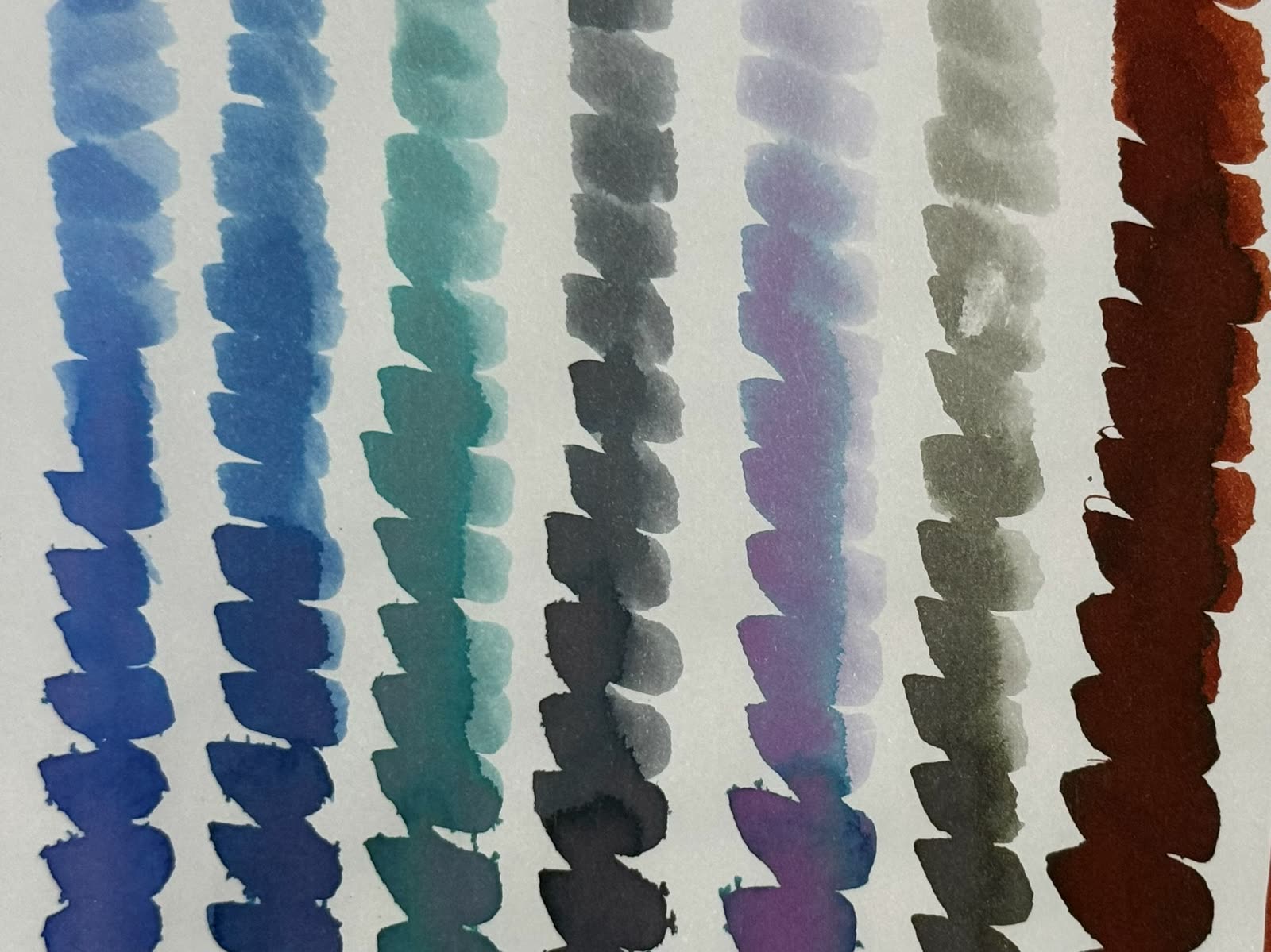 A row of colorful fountain pen ink swatches on paper from the mini-penmeet