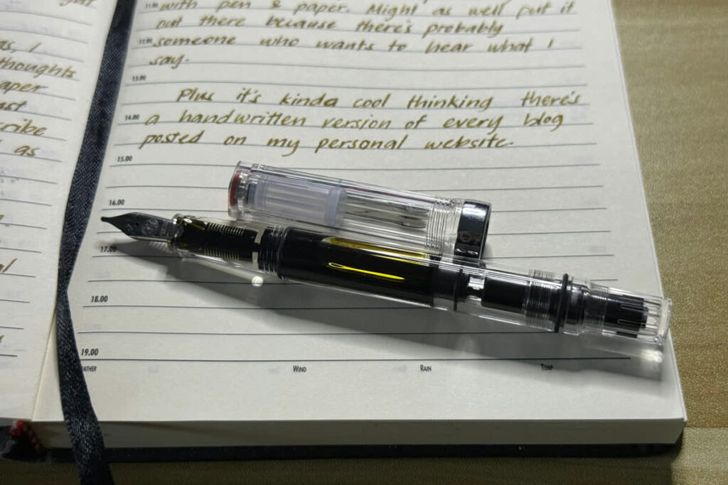 Fountain pen resting on an open journal page, the tools used to write this post by hand